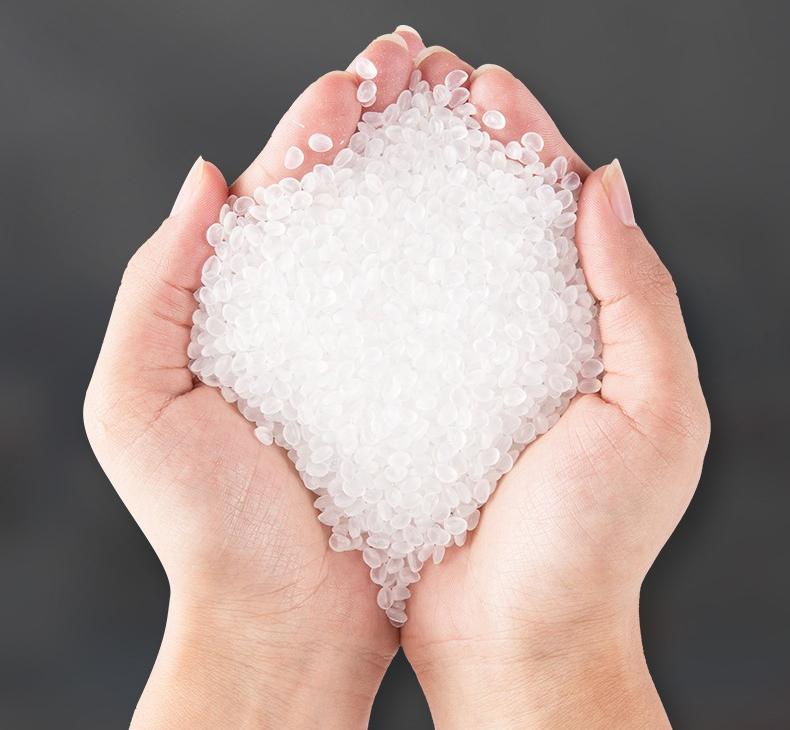Clear plastic material pellets held in two hands